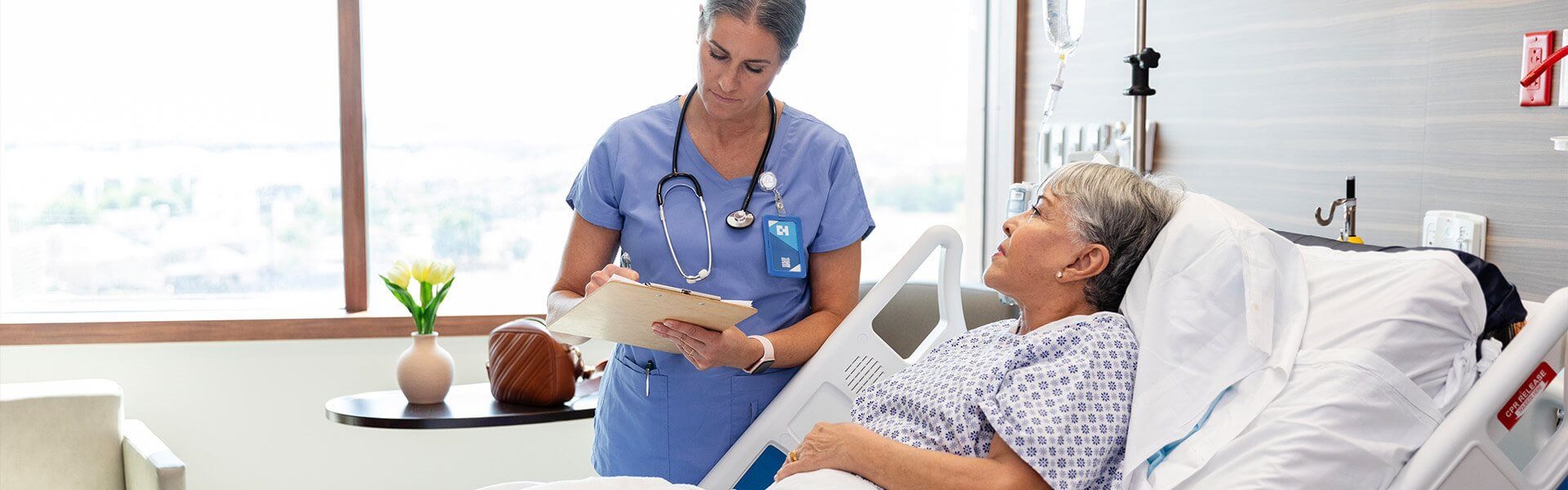 Image of a hospital reception desk with staff walking along the corridor