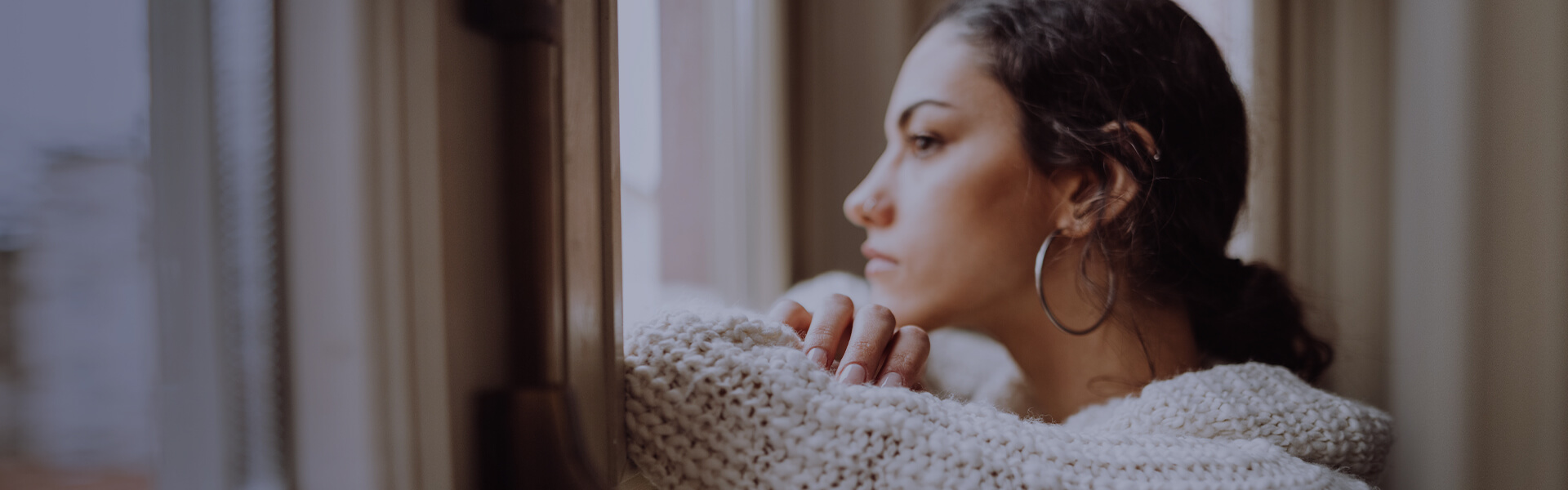 Image of woman looking thoughtfully out window